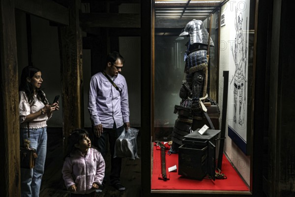 A family looks at samurai armor on display at Matsumoto Castle, Matsumoto, Japan