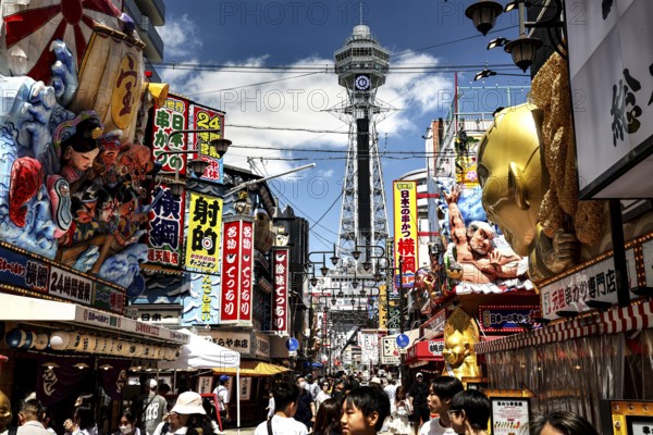 Bustling street in Shinesekai with the Tsutenkaku Tower in the background, Osaka, Japan