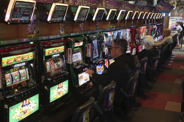 People play pachinko in a busy hall in Osaka, Osaka, Japan
