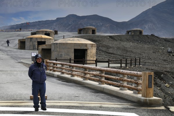 A bunker and rangers stand in the dramatic volcanic landscape of Nakadake, Aso, Aso, Kyushu, Japan