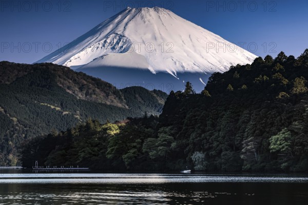 Fujiyama rises majestically over tranquil Lake Ashinoko in bright skies, Hakone, Japan