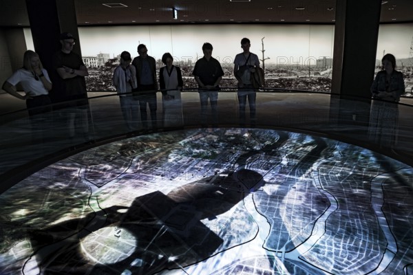 Visitors view a city model with atomic bomb simulation at the Hiroshima Peace Museum, Hiroshima, Japan