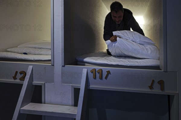 Man in sleeping capsule in a Japanese capsule hotel. Cozy and compact accommodation, Ise, Mie, Japan
