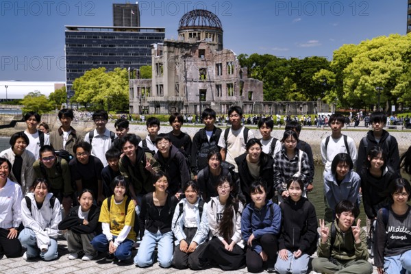 Group of students posing in front of the Hiroshima Memorial in bright sunshine, Hiroshima, Japan