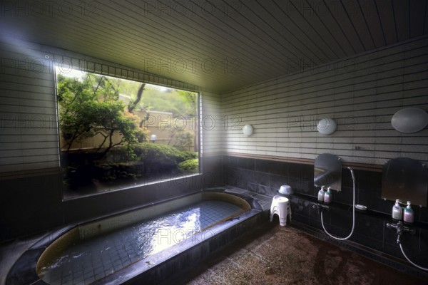 Traditional Japanese bath in ryokan overlooking a well-kept garden, Kawaguchi, Yamanashi, Japan