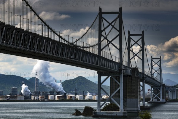 Ohashi bridge in Seto over water with industrial plants and overcast sky, Seto, Japan