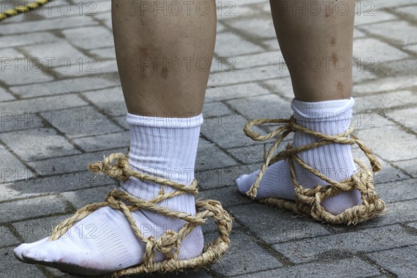 Legs in traditional straw shoes on cobblestones, Nikko, Japan