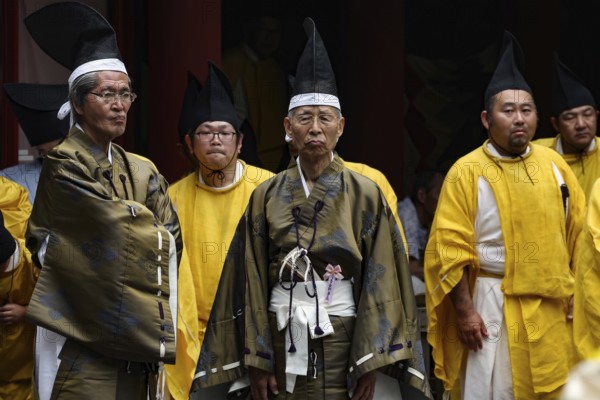 Shinto priest in festive dress wearing traditional hats in the courtyard of Toshogu Shrine, Nikko, Tochigi, Japan