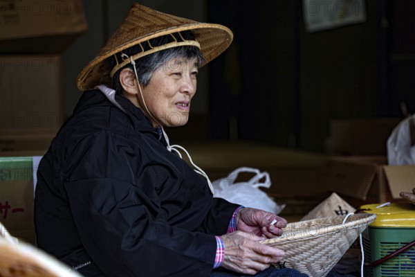 Elderly woman in Tsumago making traditional hats, Tsumago, Japan