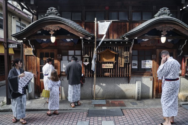 People in yukata in front of a traditional public bath, Yamanouchi, Japan