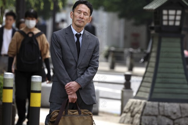Businessman in a suit holding a bag and standing on a street, Tokyo, Minato, Japan