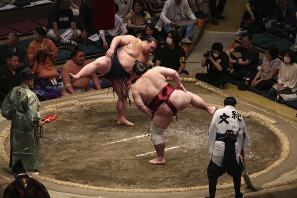Two sumo wrestlers in active combat in Kokugikan, surrounded by spectators, Tokyo, Ryogoku, Japan