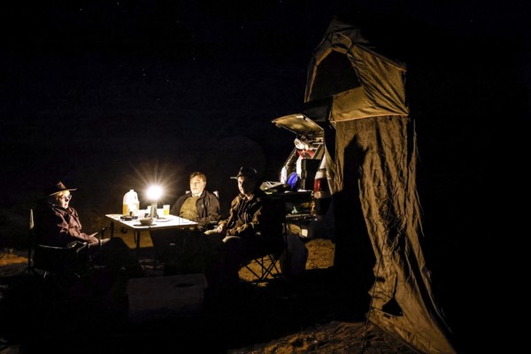 Camp at night with lights, people, vehicle in desert environment, Oodnadatta Track, Australia