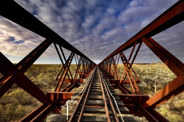Perspective view of a steel girder bridge with railroad tracks under cloudy sky, Oodnadatta Track, null, Australia