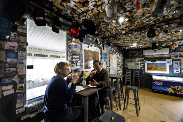 Two people in the warmly decorated and cozy interior of the William Creek Hotel, William Creek, South Australia, Australia