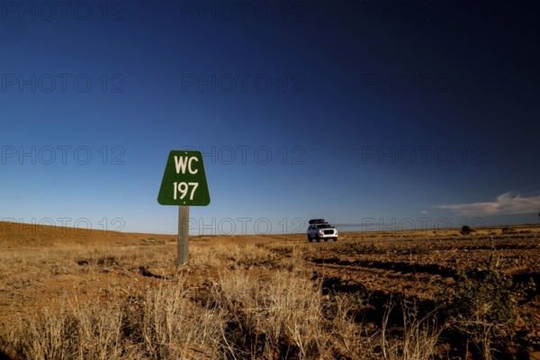 A green toilet sign on a deserted road in a dry landscape, Oodnadatta Track, Southwest Australia, Australia