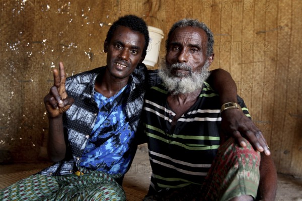 Muhammad and an elderly man pose smiling in a hut in Ahmedela, Ahmedela, Ethiopia