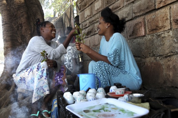 Two woman enjoy a traditional coffee ceremony and share moments of laughter, Asbe Teleri, Afar, Ethiopia