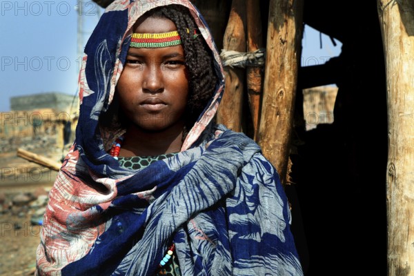 Aishe stands in front of Muhammad's Hut, Ahmedela, Tigray, Ethiopia