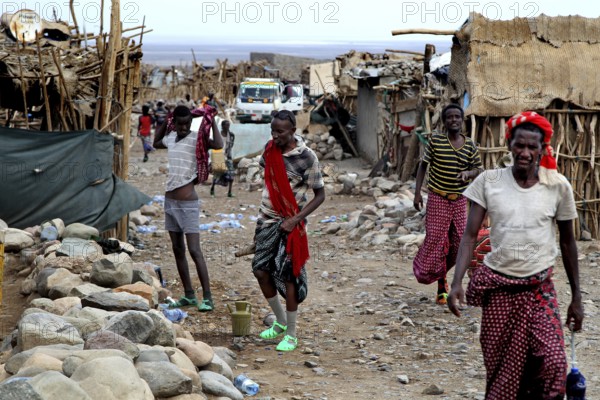Busy street in a village with traditionally dressed residents and simple huts, Ahmedela, Afar, Ethiopia