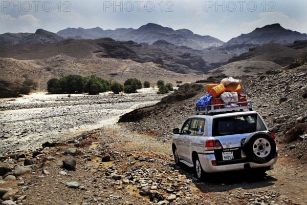 A land cruiser drives through the barren desert landscape of Ahmedela