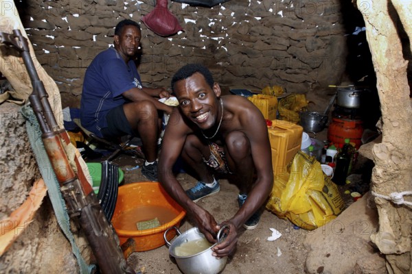 In the hut at Erta Ale Camp, two men are immersed in their work surrounded by kitchen appliances, Erta Ale, Ethiopia