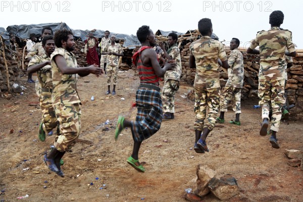 Soldiers dance in their military uniforms on rocky ground at Erta Ale Camp, Erta Ale, Ethiopia