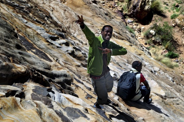 Haile and Kusay carefully climb down the rocky slopes in the Gheralta Mountains, Gheralta Mountains, Ethiopia