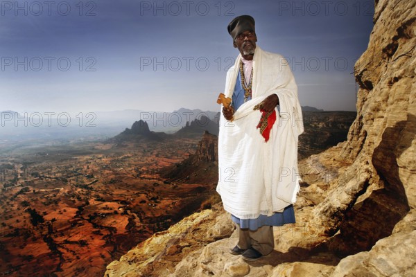 Abba Tesfay in traditional clothing with a view of the expanse of the Gheralta Mountains, Gheralta Mountains, Ethiopia