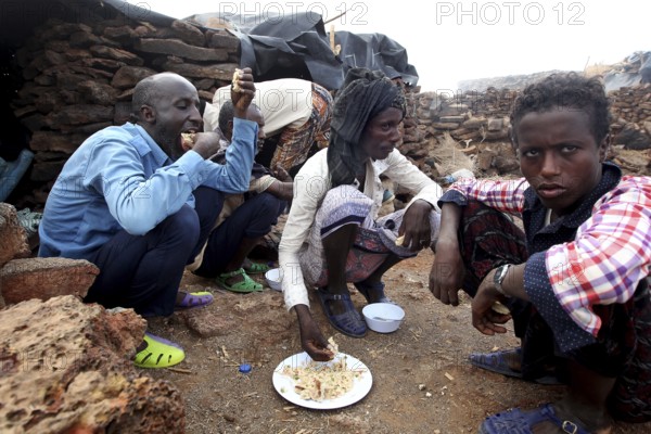 People sitting around the campfire and sharing a meal at Erta Ale camp, Erta Ale, Ethiopia