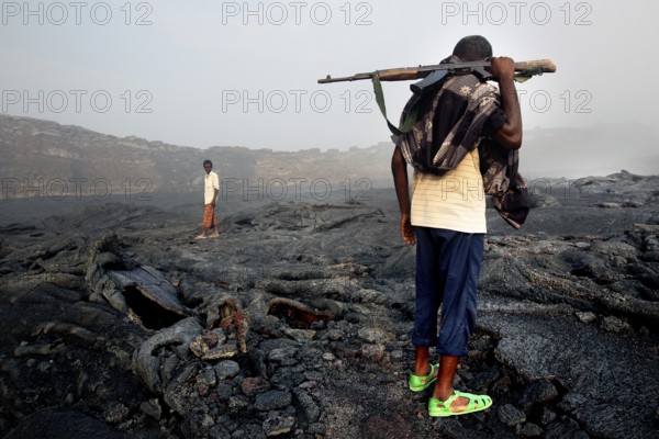 Members of the escort crew cross the volcanic terrain of Erta Ale, Erta Ale, Afar, Ethiopia