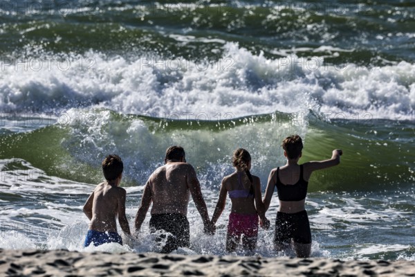Bathers enjoy the wild waves on a sunny beach in Nida, Nida, Curonian Spit, Lithuania
