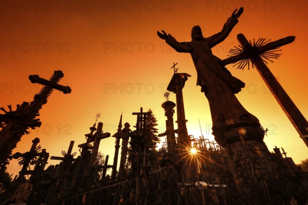 Crosses against light at sunrise on the Hill of Crosses in Siauliai, Siauliai, Lithuania