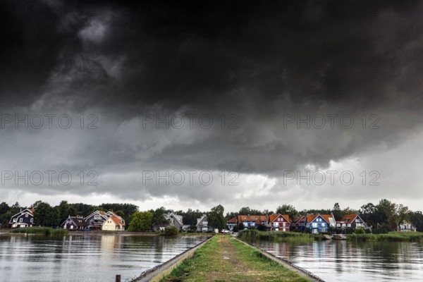 Pier leads to a village under a dramatic sky in Pervalka, Pervalka, Lithuania