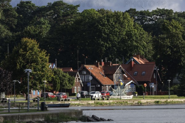 Picturesque red brick houses on the water surrounded by thick green forests, Juodkrante, Klaipeda, Lithuania