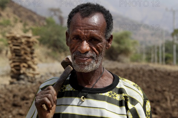 Portrait of a farmer in the Semien Mountains with ethnic clothing and tools