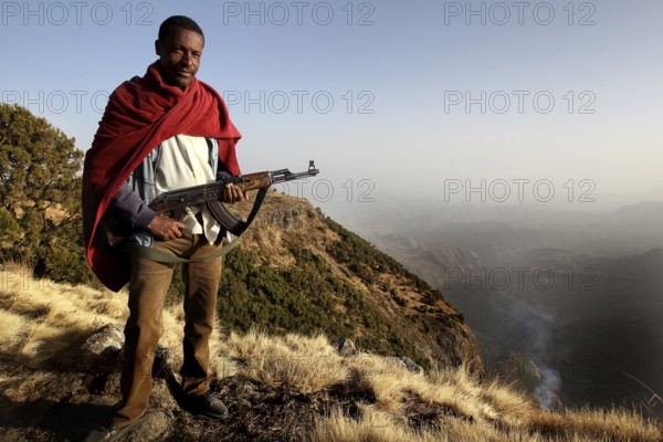 Armed companion stands in front of a vast mountain panorama in Semien Mountain National Park, Semien Mountain National Park, Ethiopia