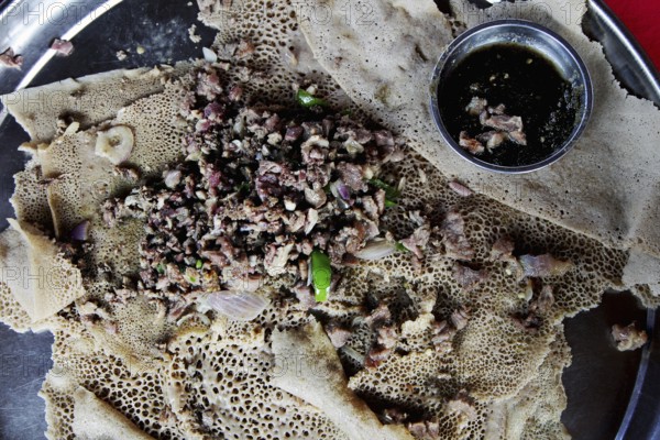 Traditional Ethiopian tibs served on injera in restaurant, Turmi, South Ethiopia, Ethiopia