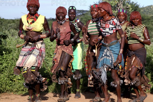 Hamer woman dance in traditional clothing during an initiation ritual. Vivid colors and traditional patterns characterize the scene, Turmi, null, Ethiopia