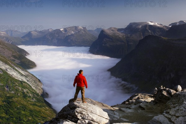 View from Dalsnibba of the Geiranger Fjord with a sea of clouds, enjoyed by a hiker