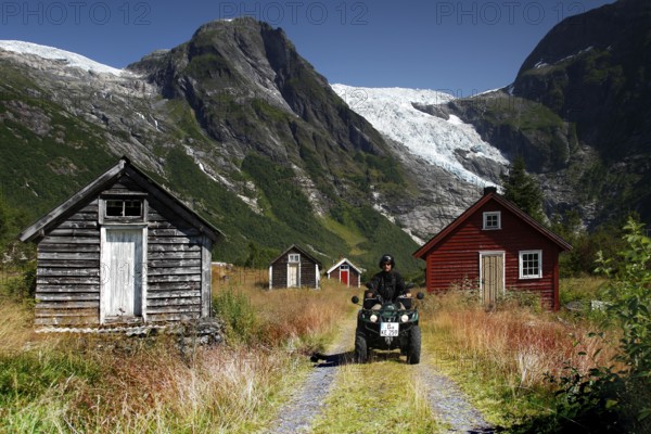 Scene near the Bøyabreen glacier with rustic huts and ATV against an impressive mountain backdrop