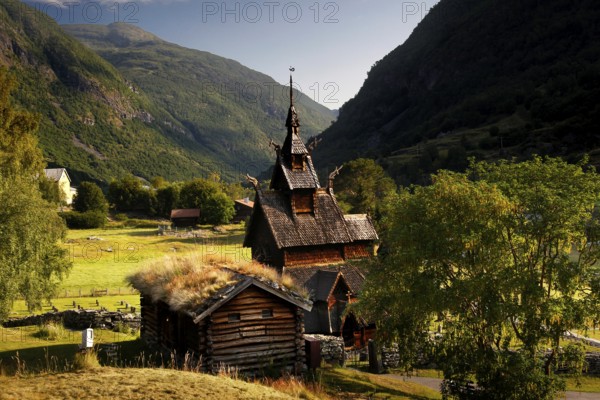 The historic Borgund Stave Church nestled in green countryside and surrounded by mountains, Borgund, Norway