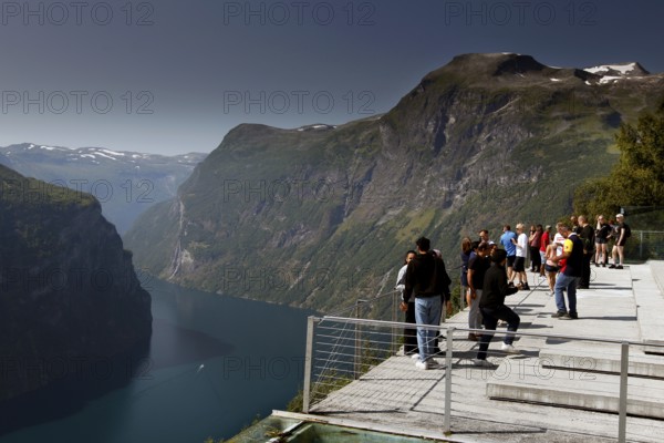 Tourists stand on an observation deck and enjoy fjord views, Geirangerfjord, Norway