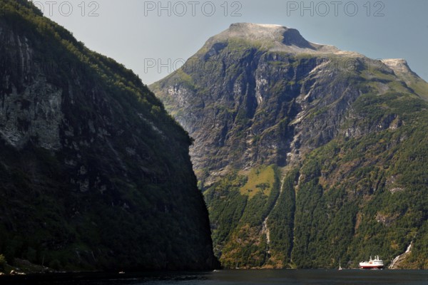 View of steep mountain walls and a Hurtigruten ship in the fjord, Geirangerfjord, Norway