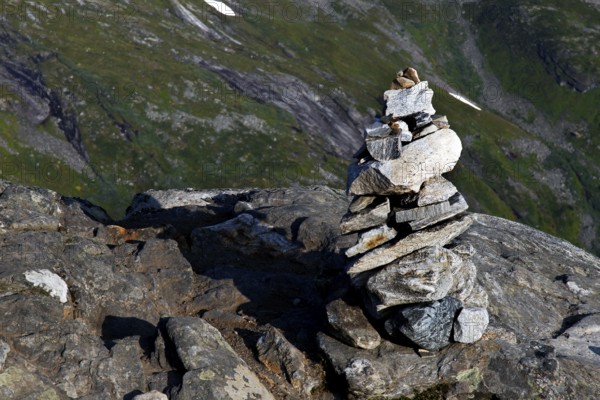 Stone pyramid on rocky outcrop with green hills in the background, Geirangerfjord, Dalsnibba, Norway