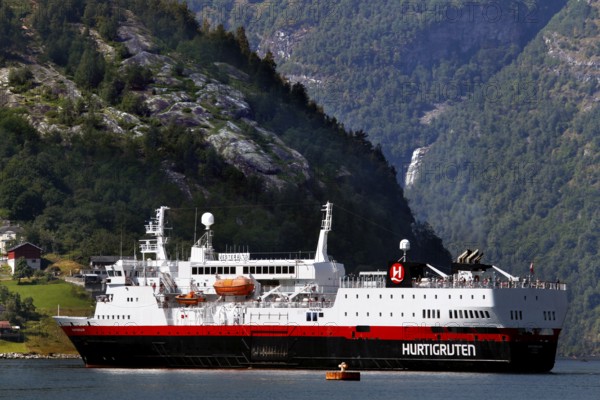 Hurtigruten ship in Geiragerfjord against a majestic coastal backdrop with waterfall