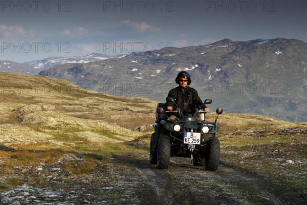 Person driving an ATV through a rugged mountain landscape under cloudy sky, zero
