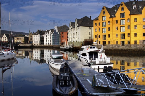 Colourful buildings and boats are reflected in the calm waters of Ålesund Harbour, Ålesund, Møre og Romsdal, Norway