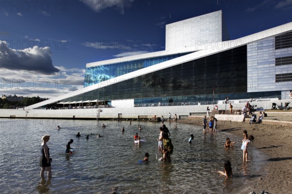 Modern opera next to beach, people enjoying sunny day in water, Oslo, Norway