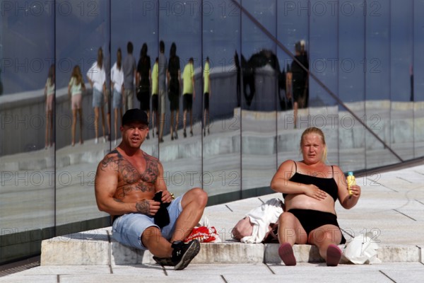 Passers-by relax in front of the reflecting façade of the opera in Oslo, Oslo, Bjøvika, Norway